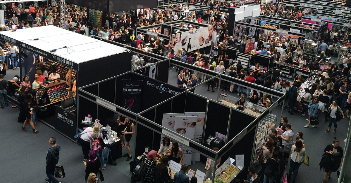 Attendees checking out booth setups at a trade show. 